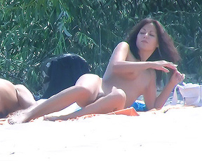 The breathtaking brunette sits at the beach naked with her lavish curves, big tits, and trimmed pussy on display.