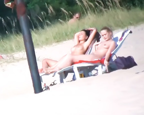 Two Nudists Sunbathing Side by Side on Beach Chairs