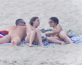 Tre naturisti condividono i teli sulla sabbia