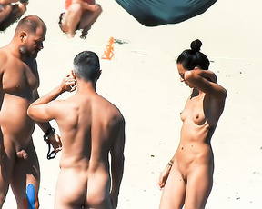 Three Nudists Standing and Talking on Sunlit Sand