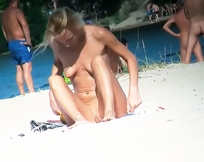 Two Nudists Sharing a Striped Towel on the Sand