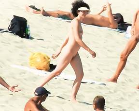 Spiaggia naturista con una borsa gialla e asciugamani sparsi