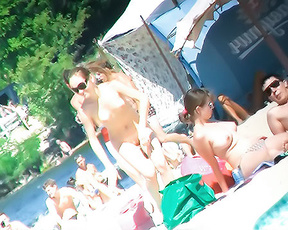 賑わうプールデッキで談笑する4人のトップレスの女性