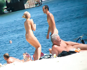 Five Naturists Gathered Near the Water with a Bicycle