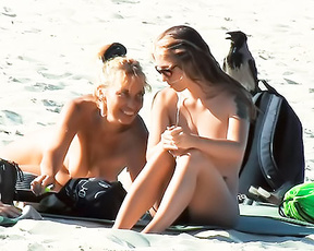 Two Nudists Sharing a Towel on Sandy Shore