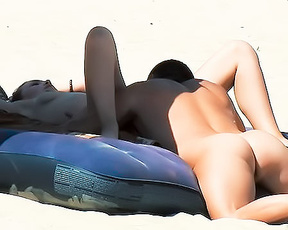 Two Nudists Sharing a Blue Inflatable Mattress on Sand