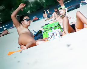 Pět nudistů odpočívajících na písečné pláži u řeky