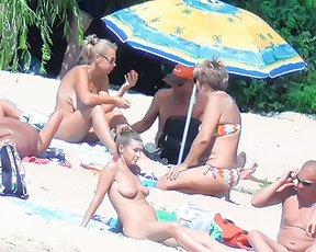 Five Naturists Gathered Around a Bright Beach Umbrella