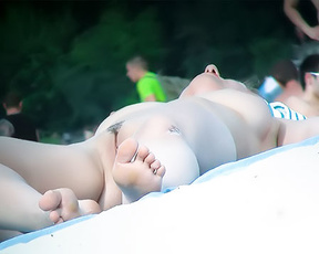 Foreground Feet and Reclining Sunbather at a Nudist Beach