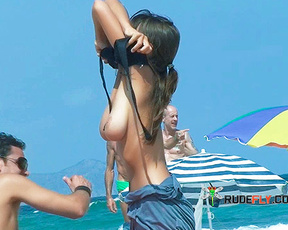 Adjusting Bikini Top on a Sunny Topless Beach