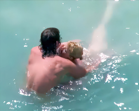 Nudists embracing in bright turquoise water with rising splashes