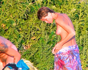 Among lush greenery, a topless woman and shirtless man relax on towels