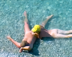 Naturistka odpočívá v mělké tyrkysové vodě