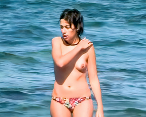 Topless beach woman standing in the bright blue sea