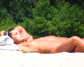 An adorable nude beach girl caught on a hidden camera sitting around at the beach