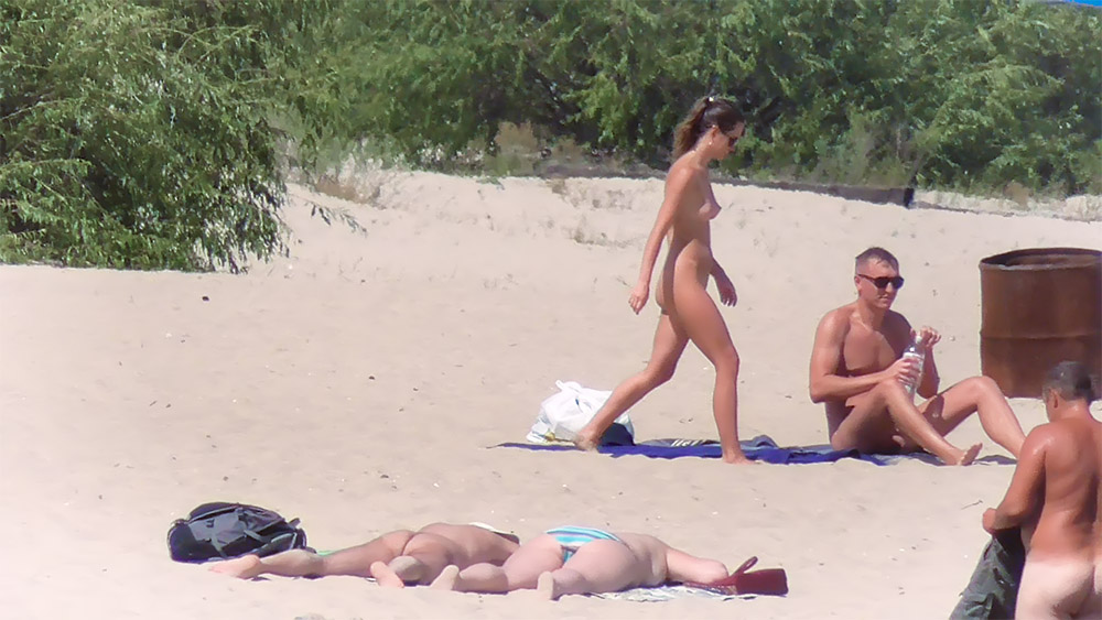Two Nudists on a Blue Towel by the Shoreline