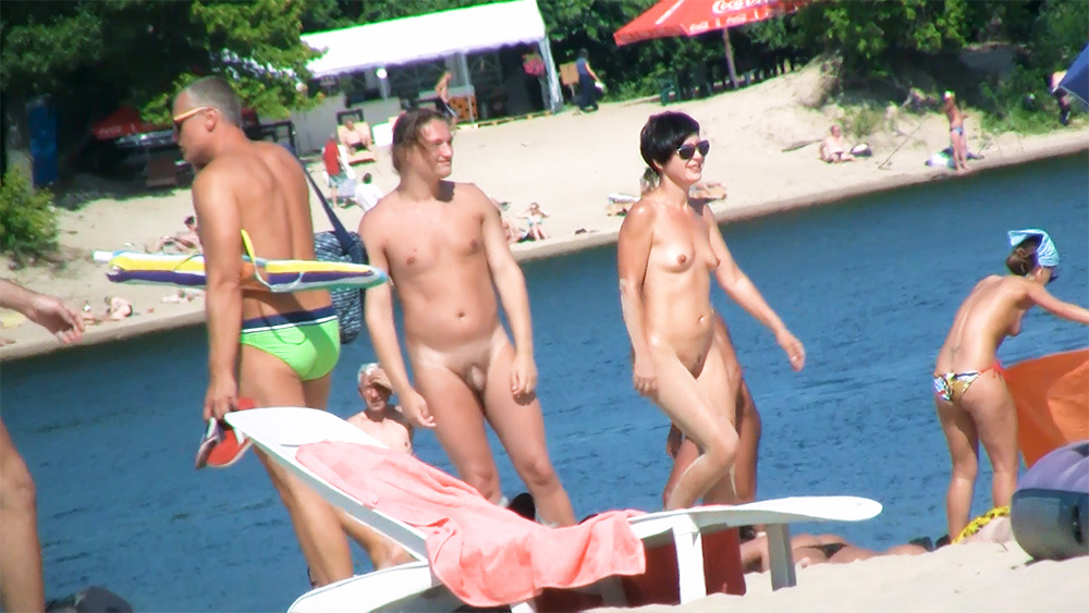 Em pé à beira do lago numa praia de nudismo