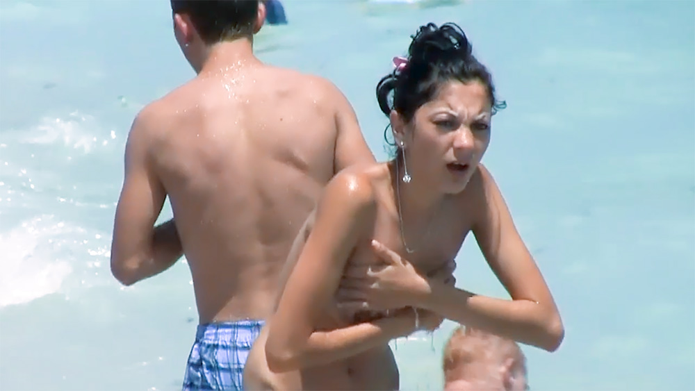 Playful brunette nudist teen caught on camera topless at the beach