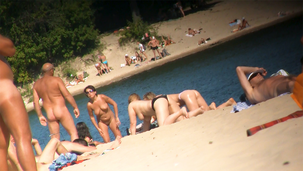 Four Naturists Gathered on a Sunlit Sandy Shoreline