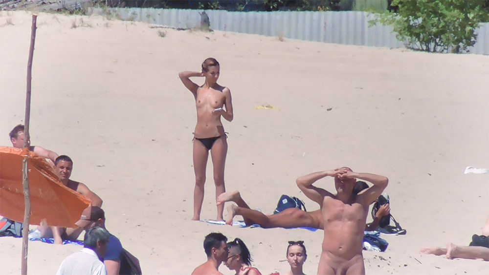 Topless kobieta i siedzący nudyści na piasku