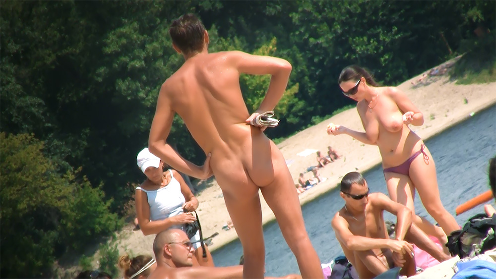 Sistemando lo slip viola del bikini su una spiaggia topless