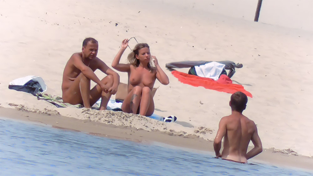 Nude Beach Couple Sitting on a Towel with Water Bottle