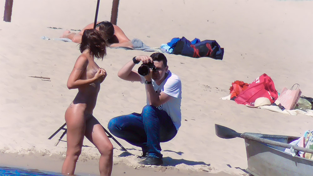 Photographer Crouching to Shoot a Topless Beach Model