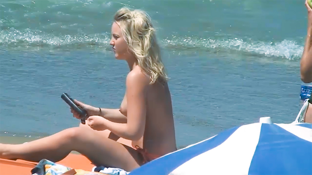 Ręcznik na plaży topless przy falach w pomarańczowych majtkach