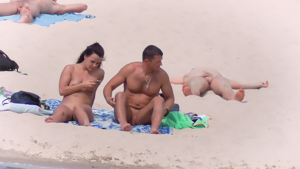 Páry na nudistické pláži se vyhřívají na slunci