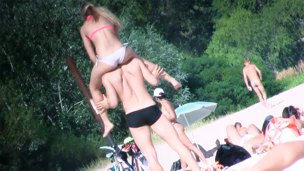Tres bañistas de playa de topless jugando junto a los árboles