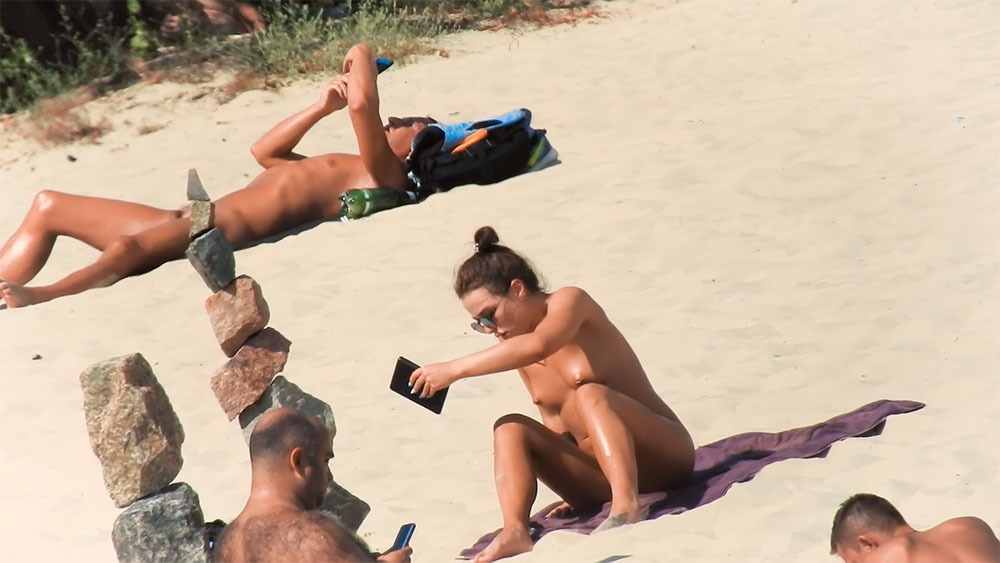 One Nude Beach Sunbather Kneeling on a Sandy Towel