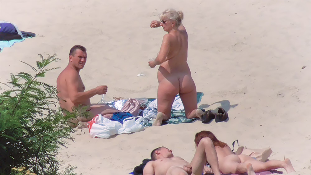 Quattro naturisti condividono un posto sabbioso in spiaggia