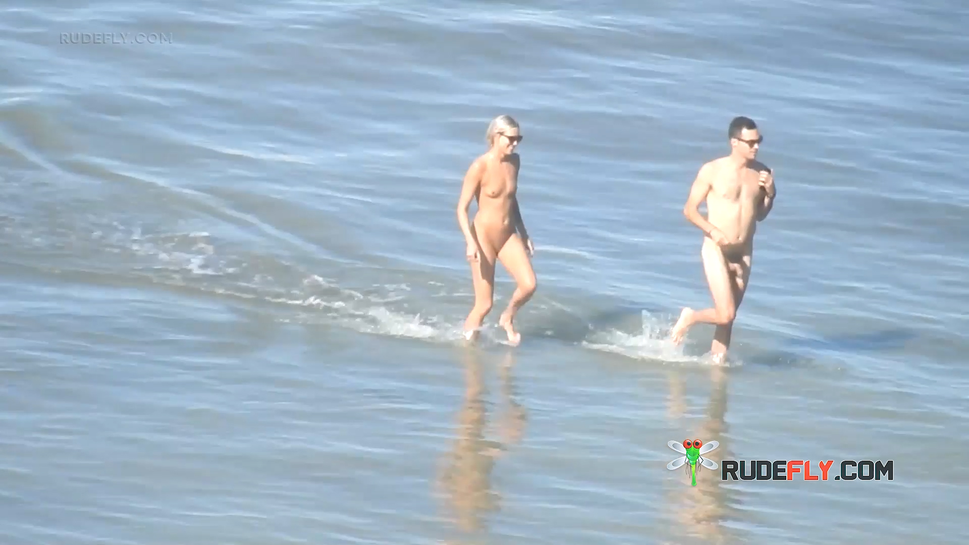 Nude Beach Couple Stepping Through Shallow Waves