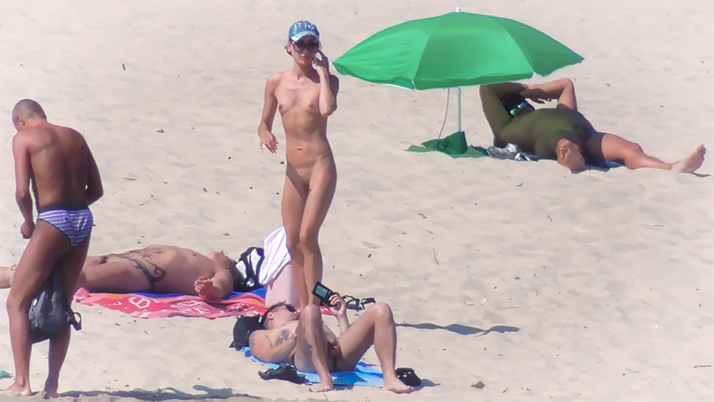 Chvíle na nudistické pláži u zeleného slunečníku a ručníků