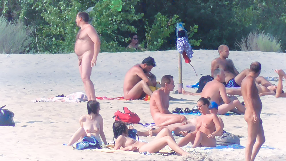 Sezení a stání spolu na nudistické pláži