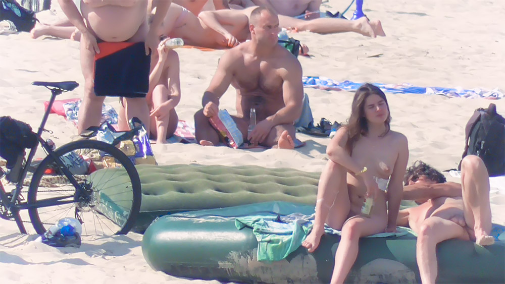 Quatro nudistas reunidos à volta de um colchão insuflável de praia