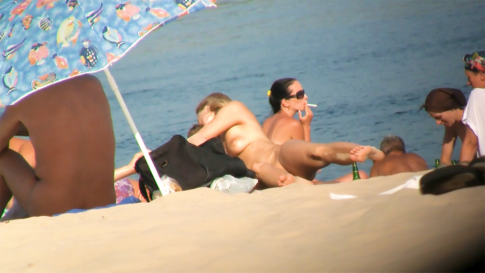 Três Mulheres Relaxadas em Topless numa Praia Solarenga