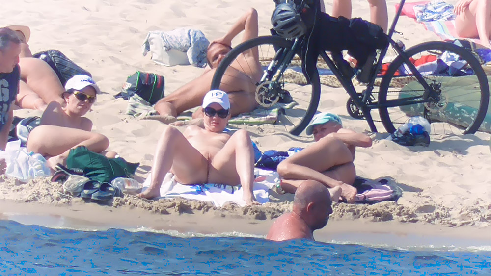 Three Nudists Lounging on a Sandy Beach