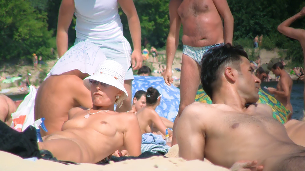Bílý klobouk a náhrdelník na plné nudistické pláži