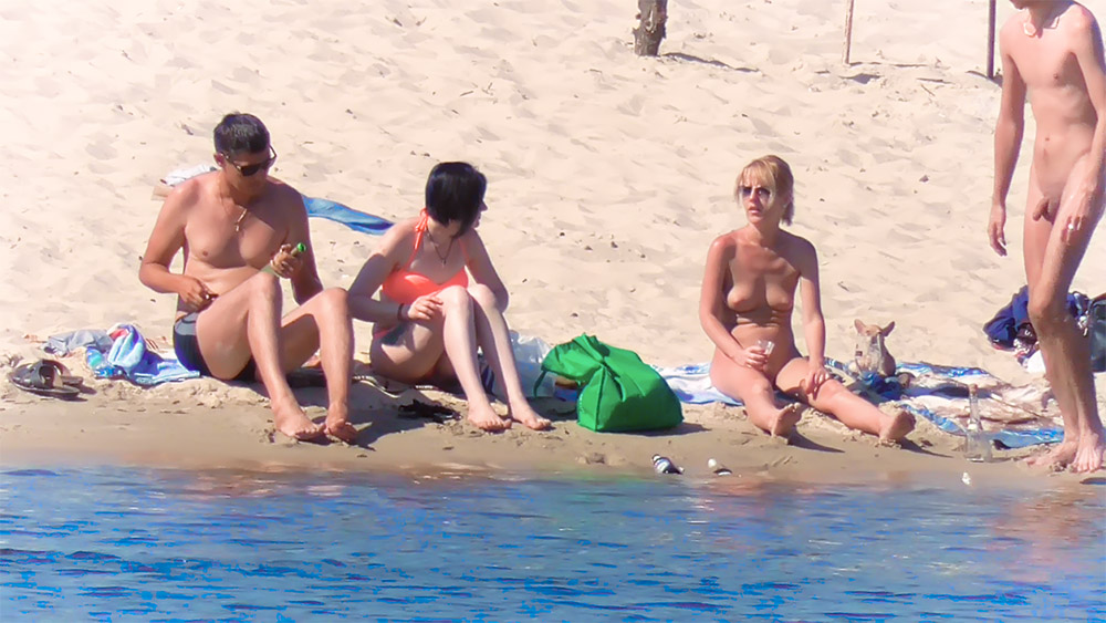 Handtuchszene am FKK-Strand mit grüner Tasche und Hund