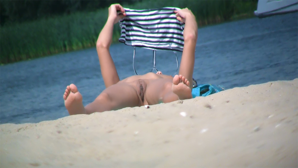 Lifting a Striped Top While Lying on a Nude Beach