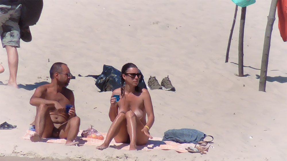 Ručník z nudistické pláže vedle turistických bot a tašky