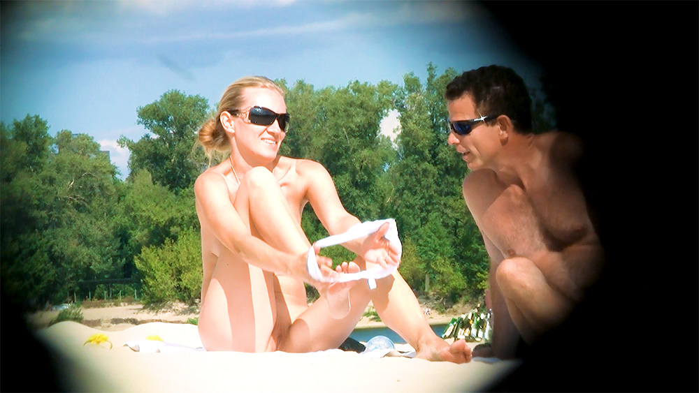 Two Nudists in Sunglasses Sharing a Riverbank Moment