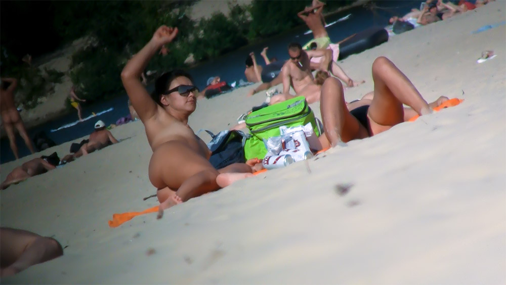 Pět nudistů odpočívajících na písečné pláži u řeky