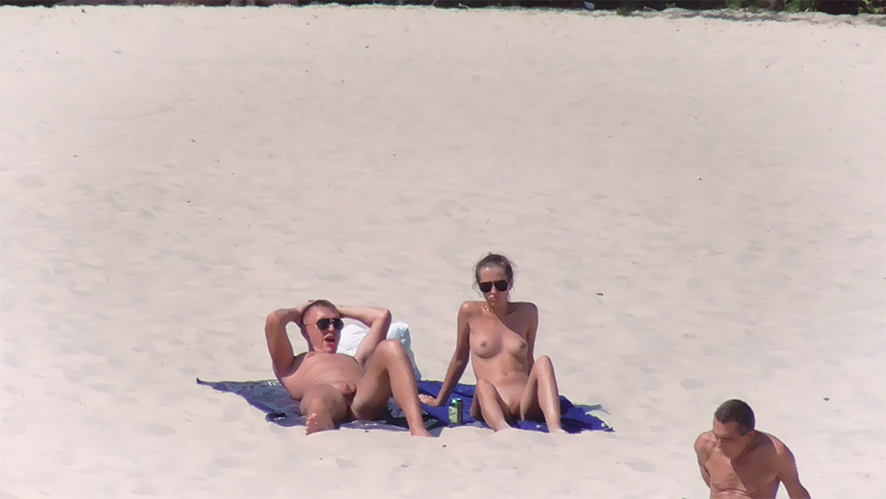 Two Nudists Lounging Together on a Sandy Beach