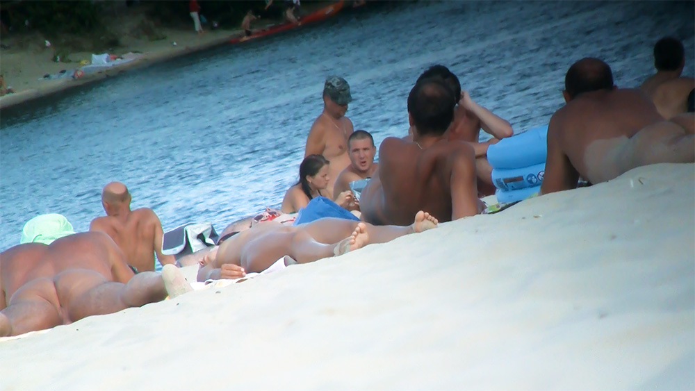 Kamienista plaża naturystów z niebieskim ręcznikiem