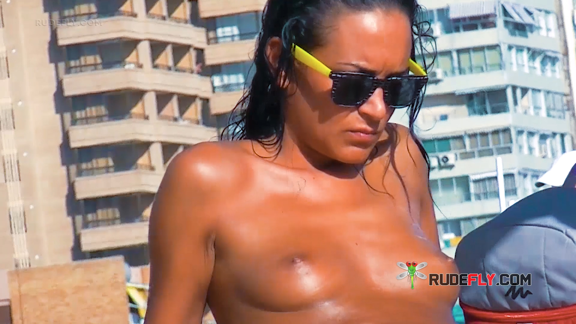 Relaxed Beachgoers Basking in the Sunlight Without Tops at Andalusian Coast