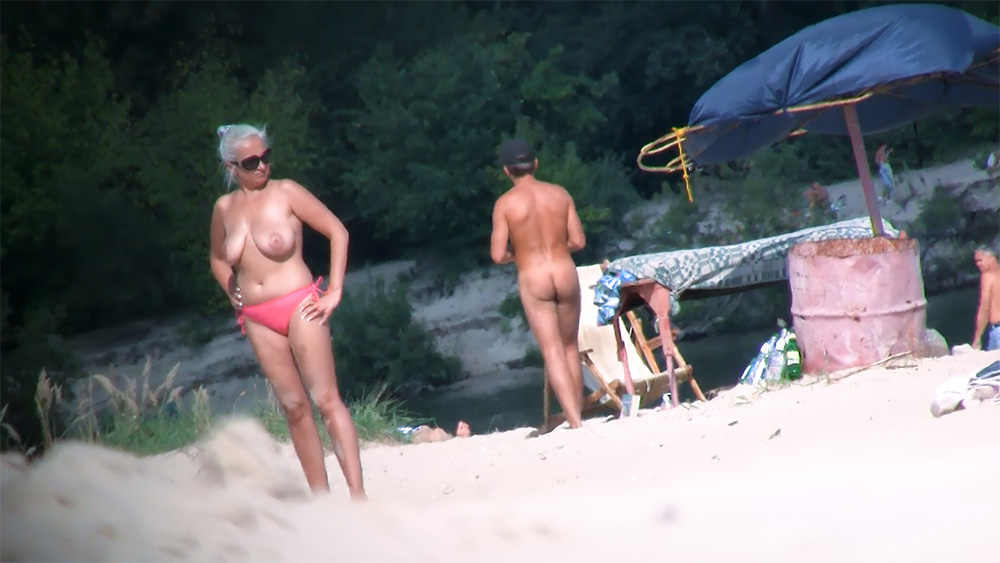 Two Naturists Pausing on a Quiet Sandy Shore