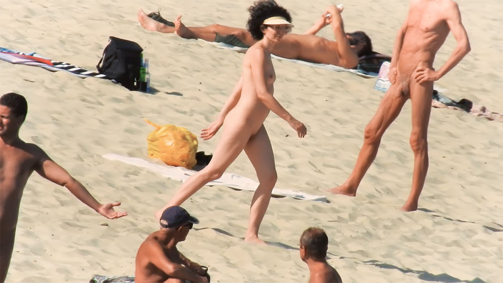 Spiaggia naturista con una borsa gialla e asciugamani sparsi