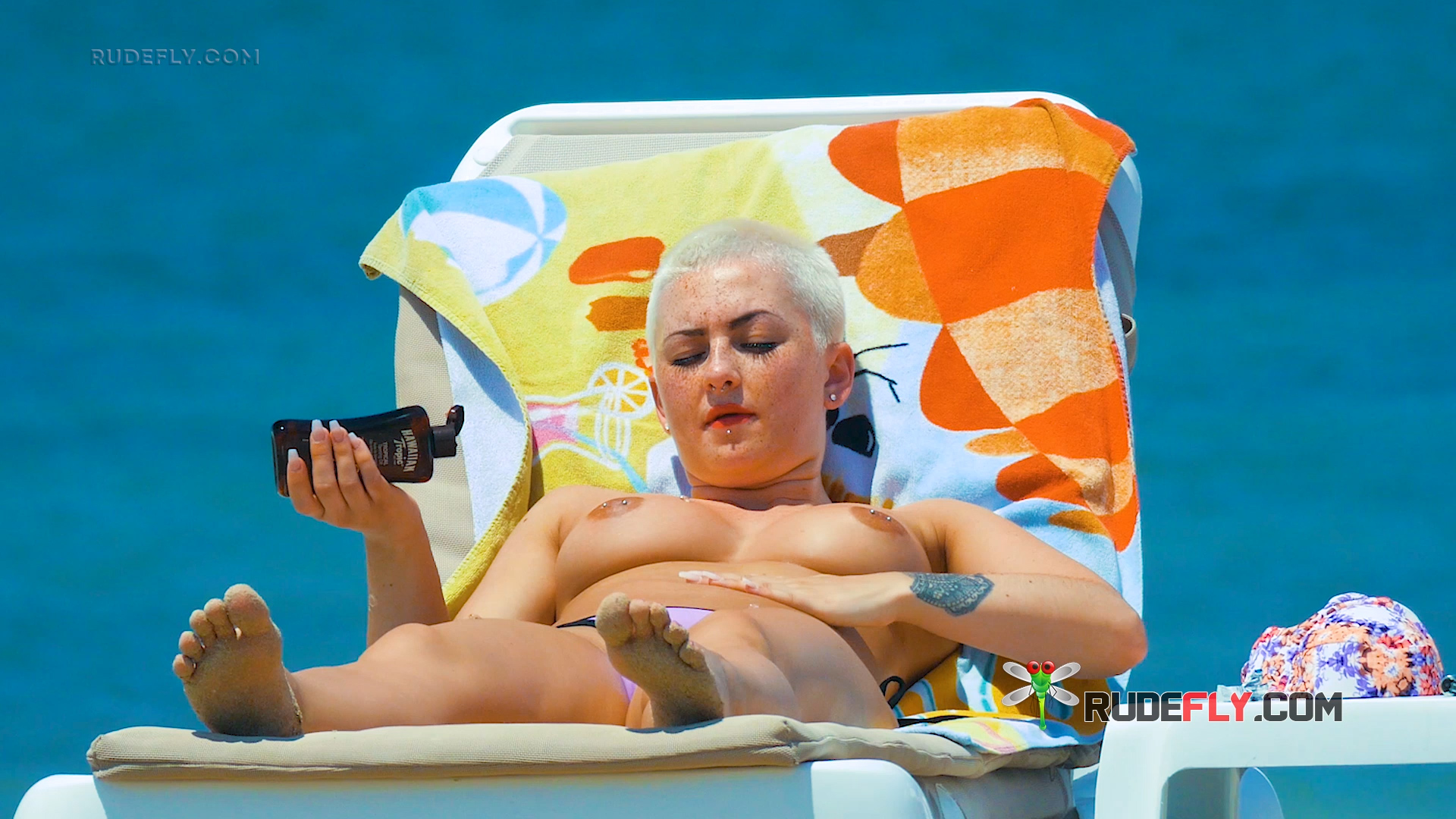 Applying Sunscreen Topless on a Seaside Beach Lounger